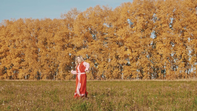 身着红色民族长裙的金发女子站在黄色场地上，手持两把剑击剑视频下载