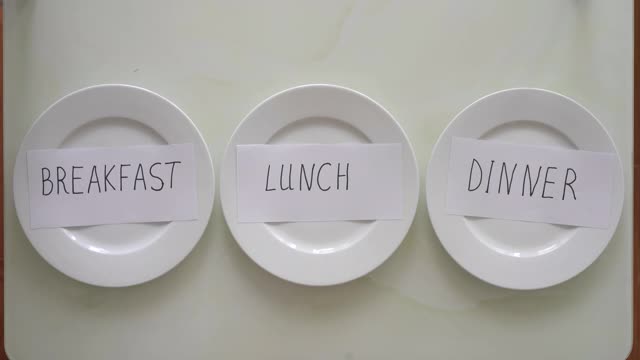 早餐，午餐和晚餐桌上的空盘子。女人用禁食取代了晚餐。间隔禁食的概念。不吃饭视频下载