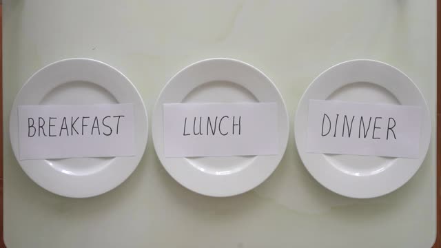 一名妇女用禁食代替空盘子上写的早餐、午餐和晚餐。间隔禁食的概念。不吃饭视频下载