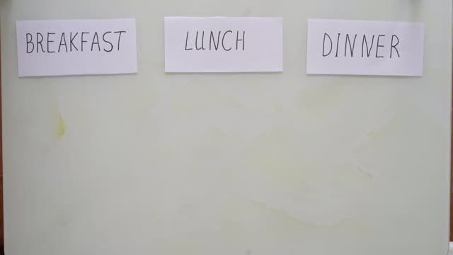 一个女人的手把一盘糙米和蔬菜下的标题午餐和标题早餐和晚餐她把空盘子与标题禁食。间隔禁食的概念。不吃饭视频下载