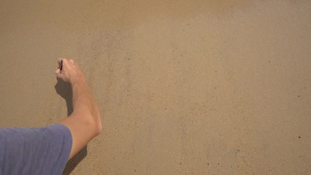 Slowmotion射杀。一个男人在沙滩上写下了2022。人生观念的变化。岁月的变迁视频素材