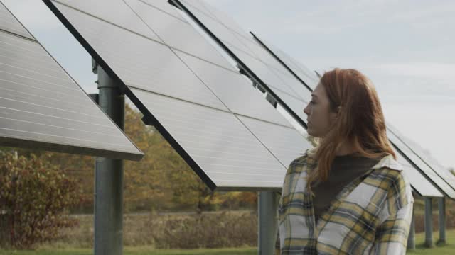 一名年轻女子走在太阳能电池板旁边视频下载