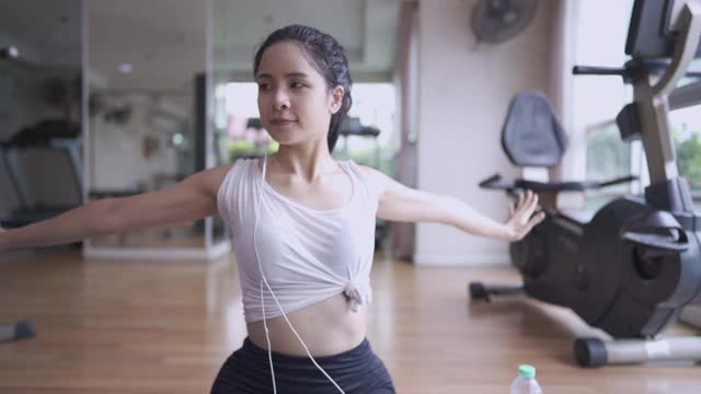 年轻活跃美丽的亚洲女人坐在地板上做过头手臂和肩膀的伸展，放松艰苦的锻炼后，灵活的肌肉身体部分，平静的深呼吸控制，瑜伽练习视频素材