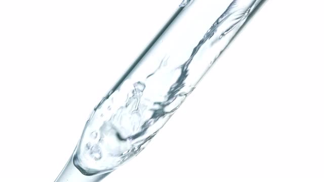 近距离和超级缓慢的运动，清水冒泡倾倒在一个透明的移液管内，放置在白色背景对角线上视频素材