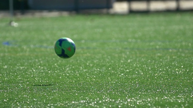 一个球和男孩的腿在草坪上踢青年足球的细节。——慢动作视频素材