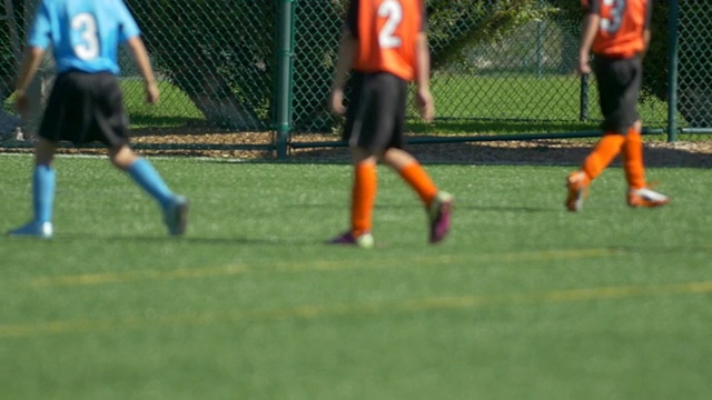 一个球和男孩的腿在草坪上踢青年足球的细节。——慢动作视频素材
