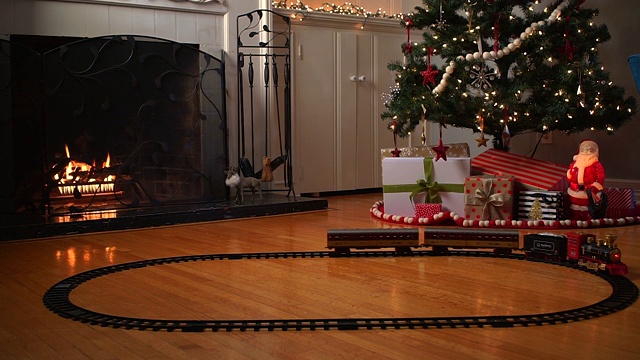 在圣诞树下的铁轨上运行的玩具火车视频素材