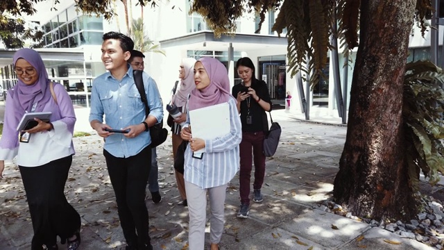 一群亚洲大学生从教育楼走出来谈话视频素材