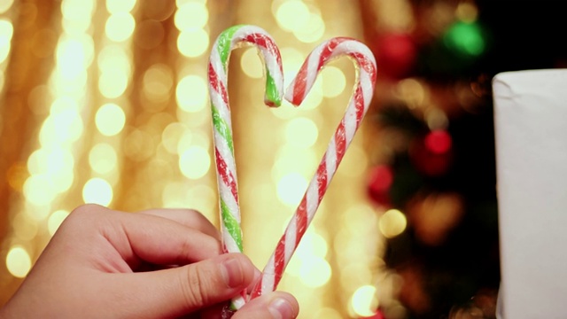 手握糖果拐杖心形圣诞灯的背景。视频下载