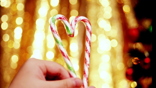 手握糖果拐杖心形圣诞灯的背景。视频下载
