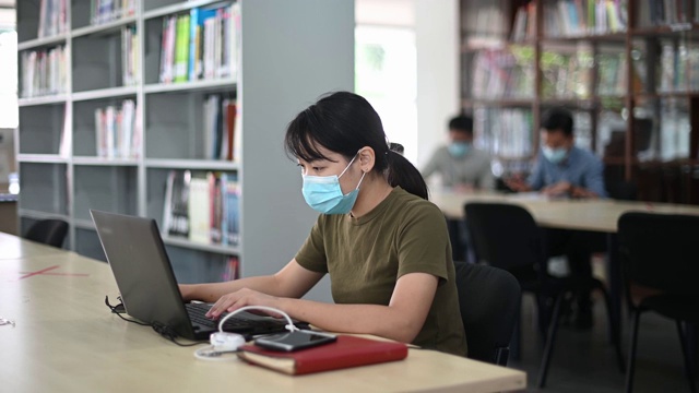 在图书馆学习的亚洲大学生观察社会距离视频素材