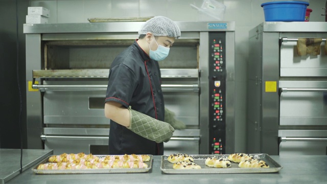 商业厨房面包店老板从烤箱中取出面包视频下载