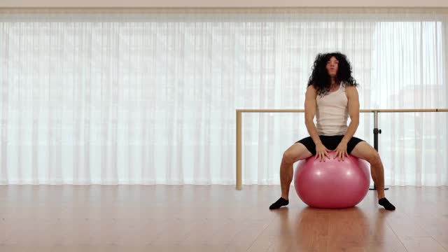 肌肉男的长假发伸展在粉红色的健身球上视频下载