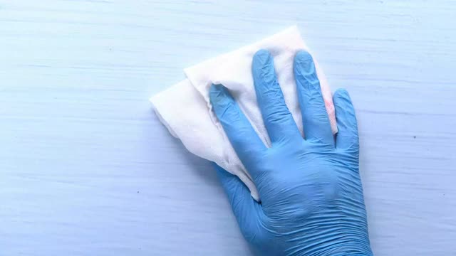 手戴蓝色橡胶手套，用布清洁桌子视频下载