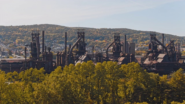 钢铁大厦——历史悠久的钢铁厂，曾经被遗弃，但现在被改造成宾夕法尼亚州伯利恒的现代文化中心。无人机视频与树木背后的平移摄像机运动。视频素材