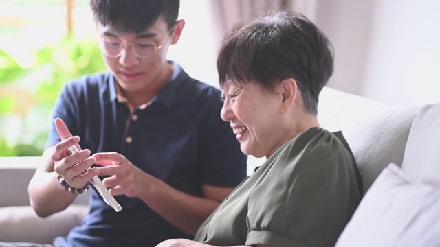 亚洲华人高级妇女看她的手机检查信息社交媒体上网冲浪视频素材