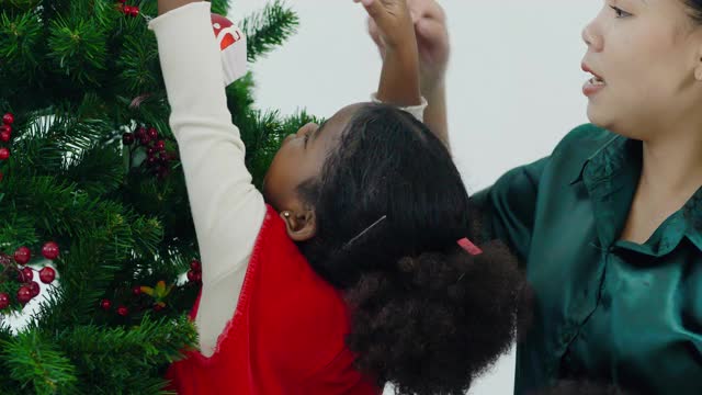 幸福的肖像给3岁的非洲裔女孩，穿着红色的衣服和家人一起准备和装饰圣诞树。圣诞精神的概念。视频素材