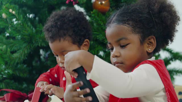 两个非洲裔儿童的幸福家庭在圣诞节通过智能手机在家里视频会议视频电话。亲密的圣诞节的概念。视频下载