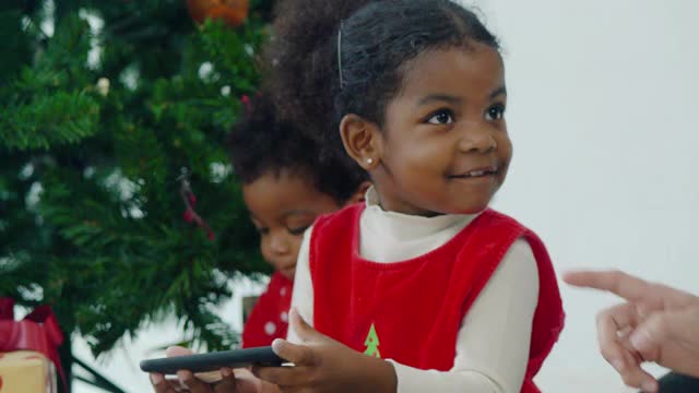 两个非洲裔儿童的幸福家庭在圣诞节通过智能手机在家里视频会议视频电话。亲密的圣诞节的概念。视频素材