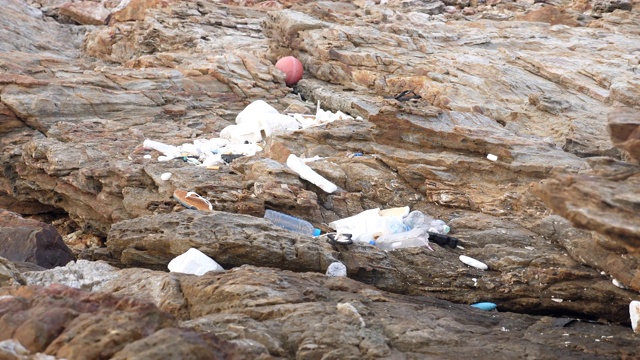 岩石海滩上的塑料垃圾，环境污染视频素材