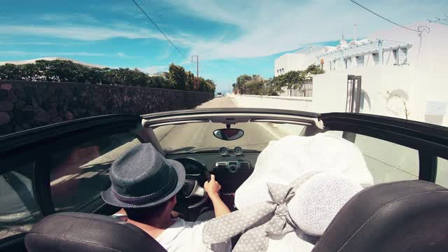 一对夫妇开着敞篷车去希腊圣托里尼岛的伊亚视频素材