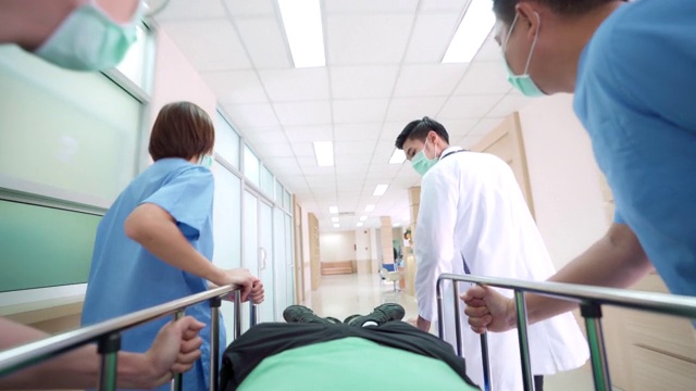 4K超高清缩小视角低角度拍摄:病人在医院轮床担架床上被医疗团队运送到医院走廊。视频素材