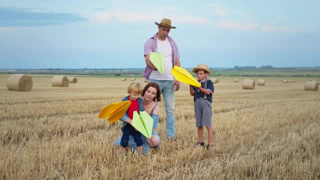 年轻夫妇和他们的儿子在乡下的周末玩纸飞机，这是一种生活方式视频下载