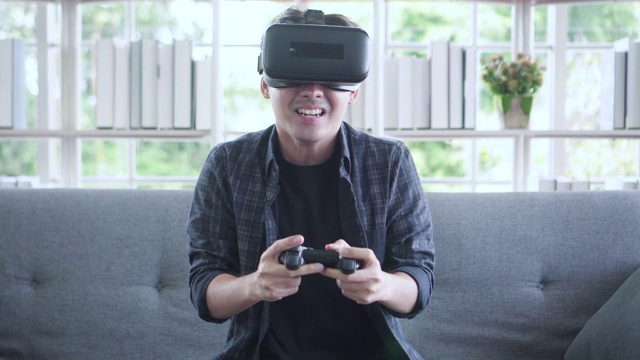 亚洲年轻人用VR眼镜和遥控器玩游戏视频素材