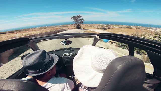 一对夫妇驾驶敞篷车在一个美丽的阳光明媚的日子，圣托里尼岛，希腊视频素材