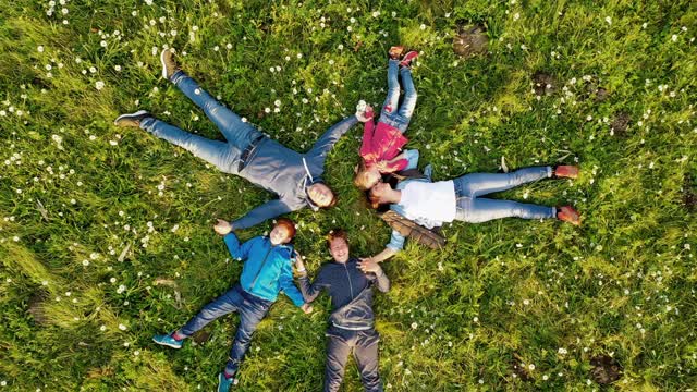 空中一家人和三个孩子围成一圈躺在草地上视频下载