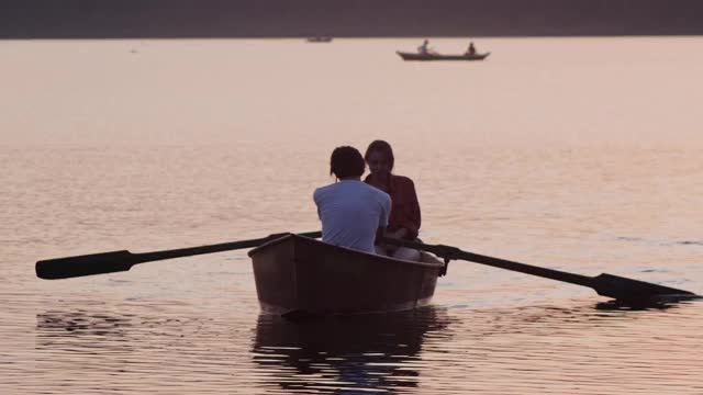 一对夫妇用桨在船上航行-美丽的日落视频下载