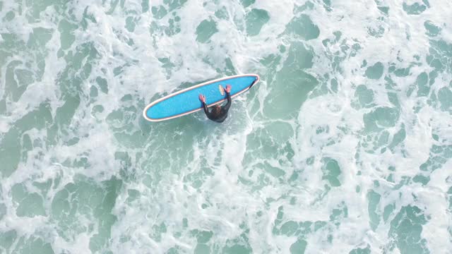 一个冲浪者试图抓住海浪和大海的鸟瞰图视频下载