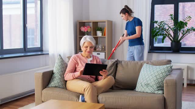 科技，老年和人的概念——快乐的老年女人用平板电脑和管家在家清洁视频下载