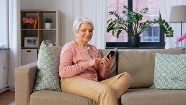 快乐的高级女性在家里用智能手机打电话视频下载