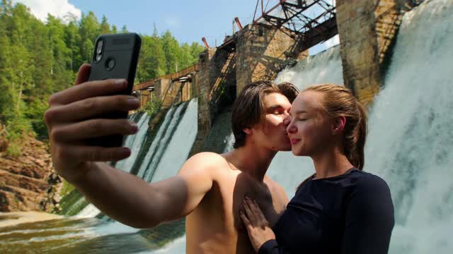 一对可爱的夫妇在森林里度假——男人和女人在大坝的背景上自拍视频下载