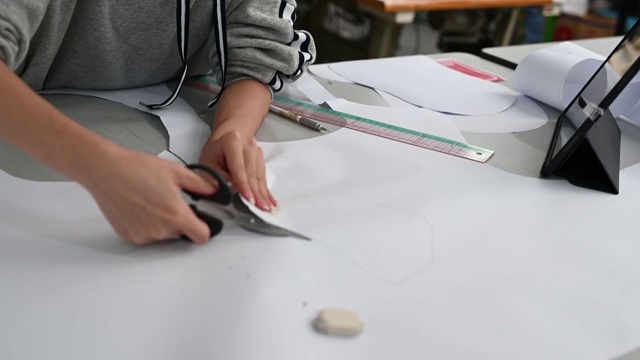 亚洲华裔女时装大学生在学院车间裁剪纸形缝制图案做服装项目视频素材
