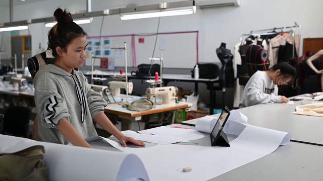亚洲华裔女时装大学生在学院车间裁剪纸形缝制图案做服装项目视频素材