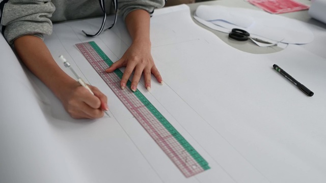 亚洲华裔女时装大学生在学院车间做服装项目，写下尺寸，画出缝纫图案视频下载