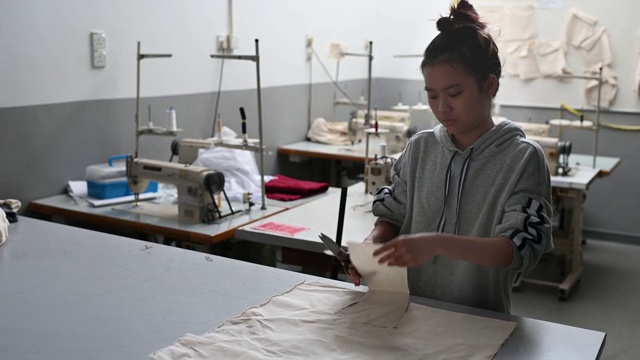 亚洲华裔时装女大学生在大学工作坊裁剪面料做服装项目视频素材