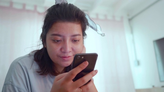 快乐的亚洲女人在家里用智能手机在线购物。视频素材