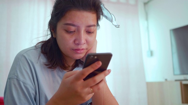 快乐的亚洲女人在家里用智能手机在线购物。视频素材