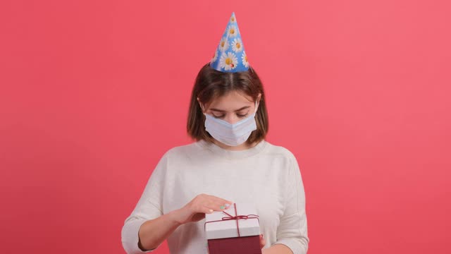 一个乐观的女孩与医疗面具的特写打开礼盒视频素材