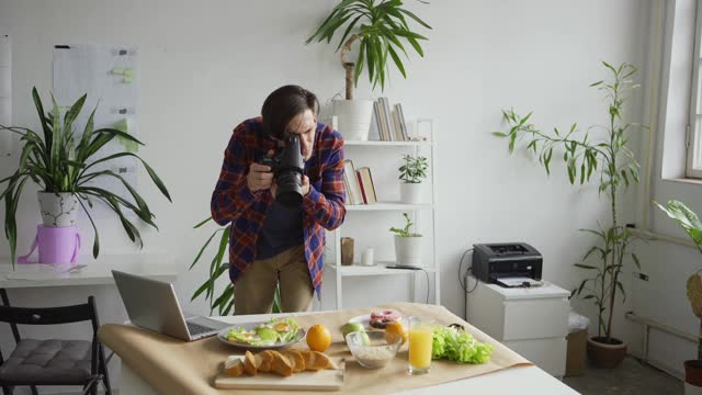 中等拍摄的年轻男性摄影师安排对象，而以食物为背景的照片与水果和食物放在桌子上的办公室视频下载