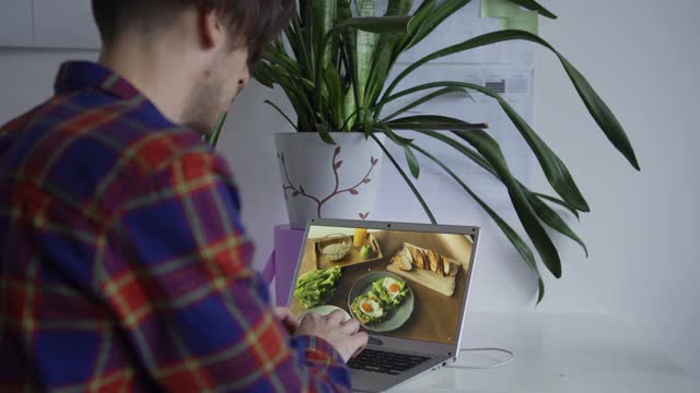 专业男性摄影师在工作室里用笔记本电脑查看照片，用桌上的食物制作平面图像视频下载