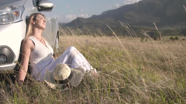 女人坐在车里，在草地上晒太阳视频下载