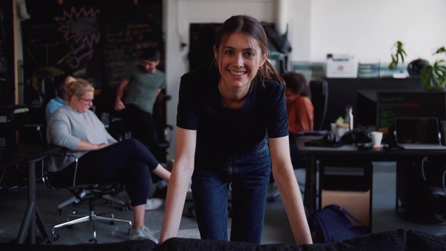 当同事们在办公室后台讨论时，自信的女电脑程序员微笑着的肖像视频下载