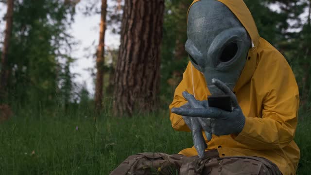 穿着黄色衣服的外星人在森林里打电话，不明飞行物概念，太空视频下载