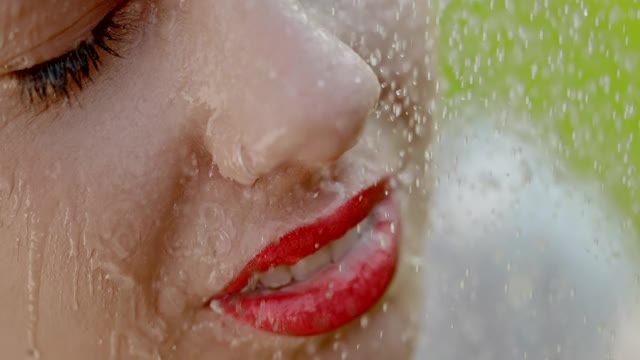 水滴落在一个年轻女子的脸上，涂着强烈的红色口红视频素材