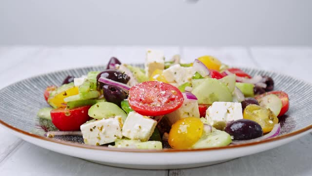 一个近距离观察服务与叉子新鲜制成充满活力的希腊沙拉从服务盘在桌子上。4K蔬菜沙拉的概念。视频下载