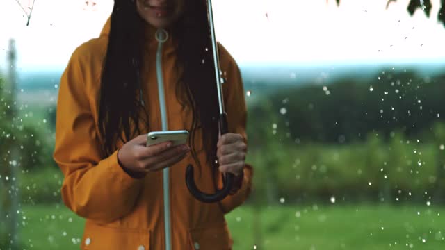 一个在雨中使用智能手机的年轻女子视频素材
